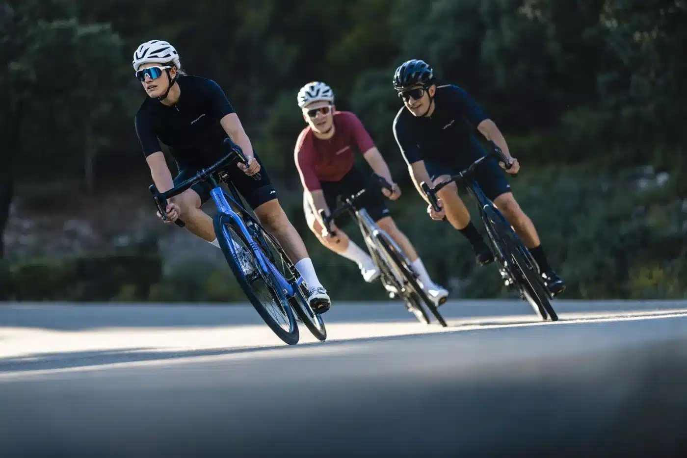 Drei Rennradfahrer mit Helm und sportlicher Kleidung auf verschiedenen Stevens Xenith Modellen, die auf einer Straße in die Ferne fahren.