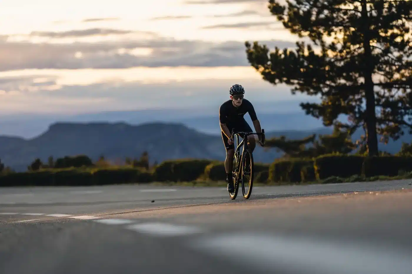 Radsportler fährt ein Stevens Xenith Endurance-Rennrad auf einer Straße mit bergiger Landschaft im Hintergrund.