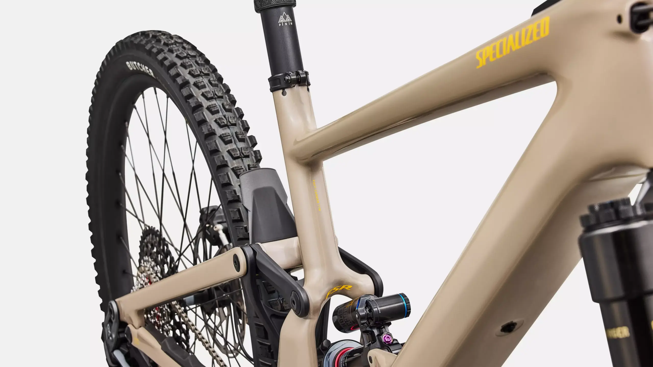 Detailansicht des sandfarbenen Rahmens eines Specialized Turbo Kenevo SL 2 Expert E-Mountainbikes mit Fokus auf Hinterradaufhängung und Reifen.