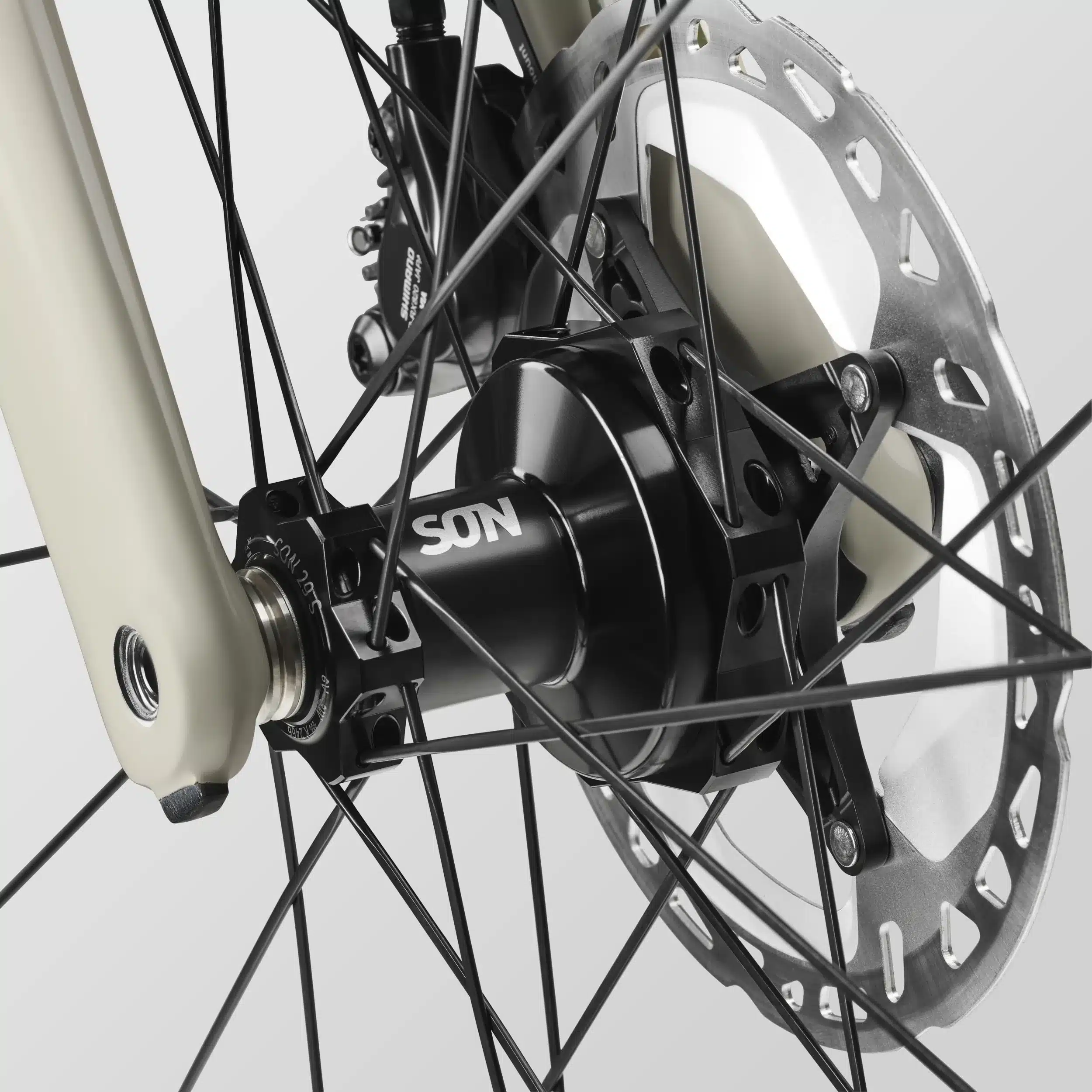 Nahaufnahme eines Fahrradnabendynamos der Marke SON, verbunden mit der Vorderradgabel und einer Scheibenbremse des Canyon Grizl CF 8 ESC.