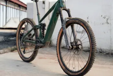 Seitenansicht eines dunkelgrünen Maxx Fab.4 Ela E-Enduro Fahrrads, das auf einem Betonboden steht.