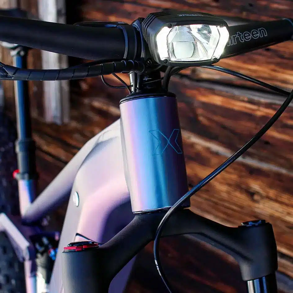 Detailansicht des MAXX Huraxdax ELS X2 E-Mountainbikes mit Fokus auf den Lenker, den leistungsstarken Scheinwerfer und das