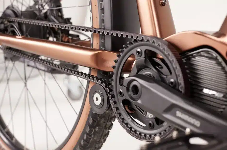 Nahaufnahme des Antriebsstrangs eines MAXX Pacemaxx ELS Tour E-Bikes mit Fokus auf den Zahnriemen, die Kurbelgarnitur von Shimano und den Motor.