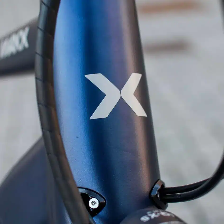 Detailansicht des Logos 'X' auf dem Rahmen eines MAXX Crossmaxx ELS E-Trekkingbikes.