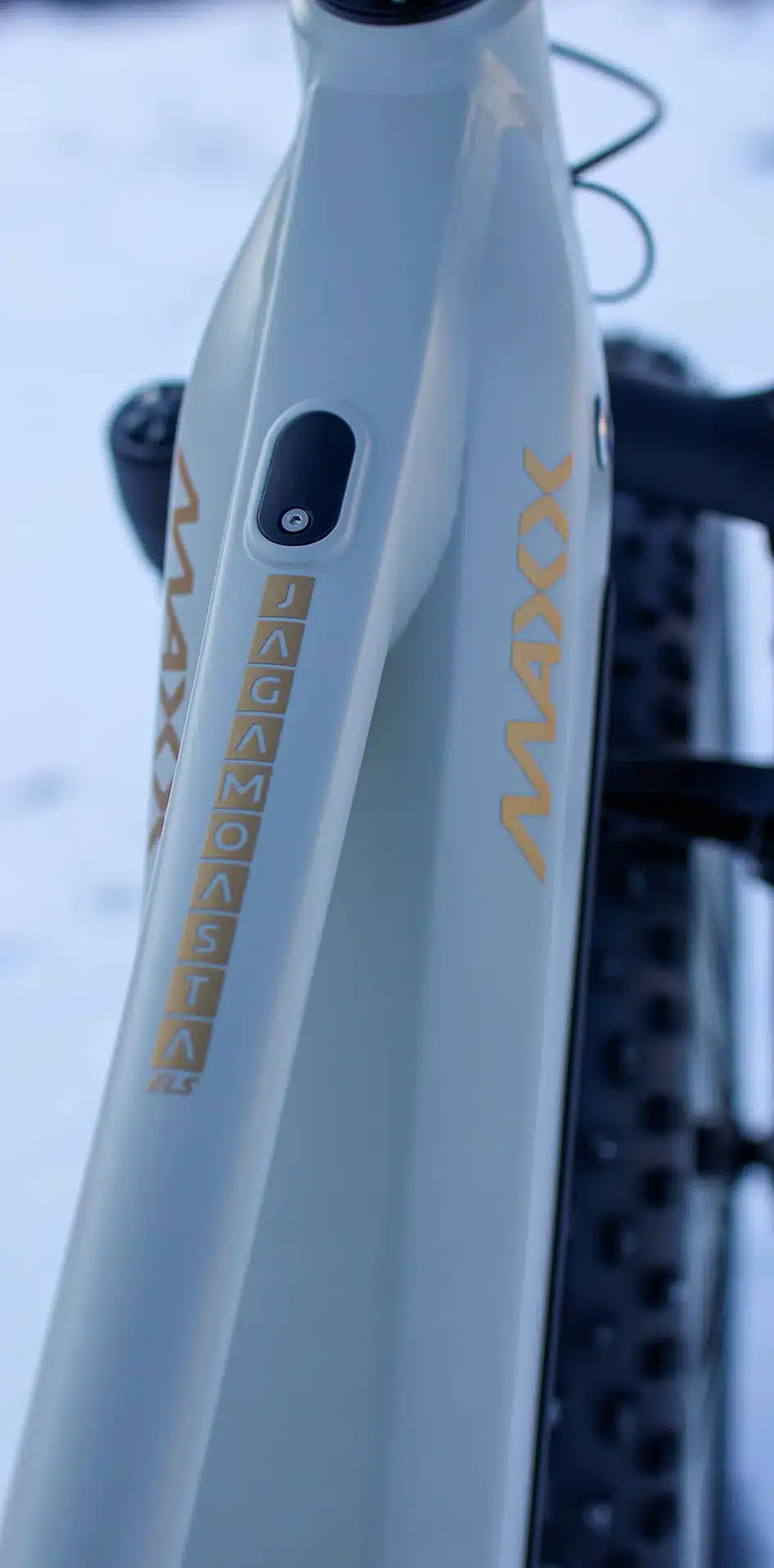 Detailansicht des hellgrauen Rahmens eines MAXX Jagamoasta ELS SH E-Fatbikes mit goldenen Schriftzügen
