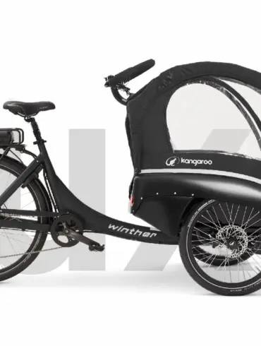 Kangaroo Luxe Lastenrad, ein schwarzes Elektro-Dreirad mit geschlossener Transportkabine für Kinder und Gepäck, mit Gepäckträger und Batterie.
