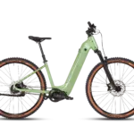 Vollansicht des MAXX Pacemaxx Comfort ELS Sport E-Bikes in Hellgrün mit Fokus auf den robusten Rahmen, die Federgabel und die breiten Reifen mit braunen Seitenwänden.