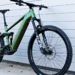 Grünes E-Mountainbike mit Diamantrahmen, Federung vorne und hinten, Scheibenbremsen und 29-Zoll-Laufrädern.