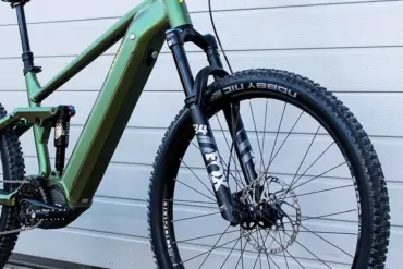 Grünes E-Mountainbike mit Diamantrahmen, Federung vorne und hinten, Scheibenbremsen und 29-Zoll-Laufrädern.