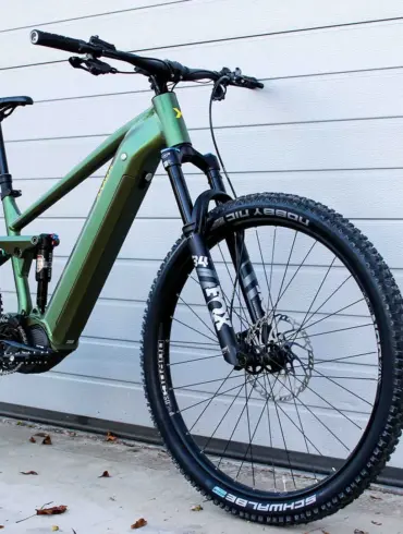 Grünes E-Mountainbike mit Diamantrahmen, Federung vorne und hinten, Scheibenbremsen und 29-Zoll-Laufrädern.