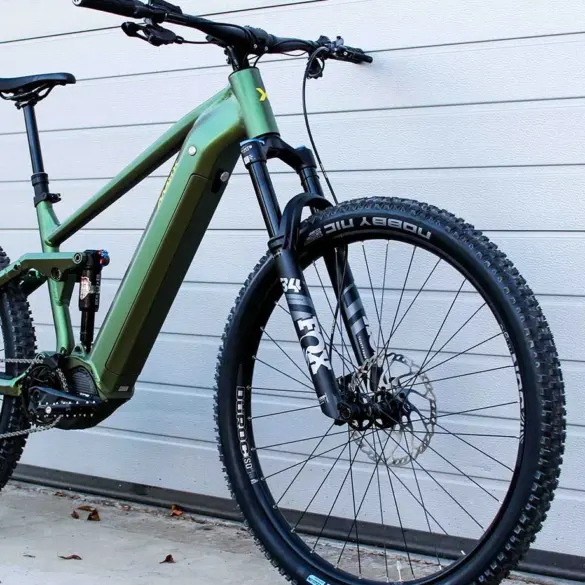 Grünes E-Mountainbike mit Diamantrahmen, Federung vorne und hinten, Scheibenbremsen und 29-Zoll-Laufrädern.