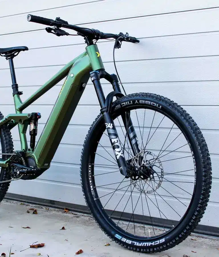 Grünes E-Mountainbike mit Diamantrahmen, Federung vorne und hinten, Scheibenbremsen und 29-Zoll-Laufrädern.