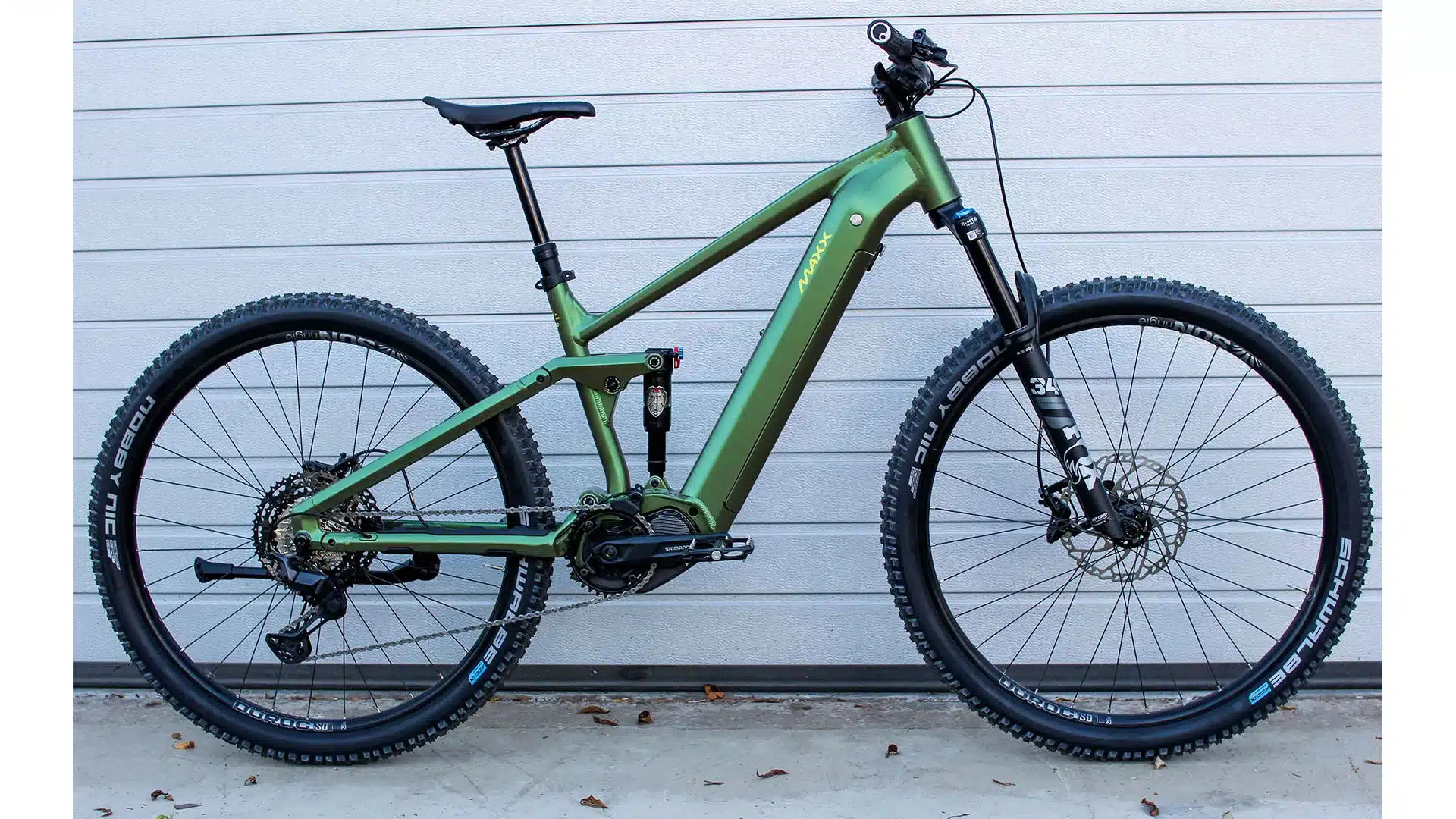 Seitenansicht eines grünen E-Mountainbikes namens Maxx Tourmaxx ELS Sport mit Schwalbe Reifen und Shimano Komponenten.