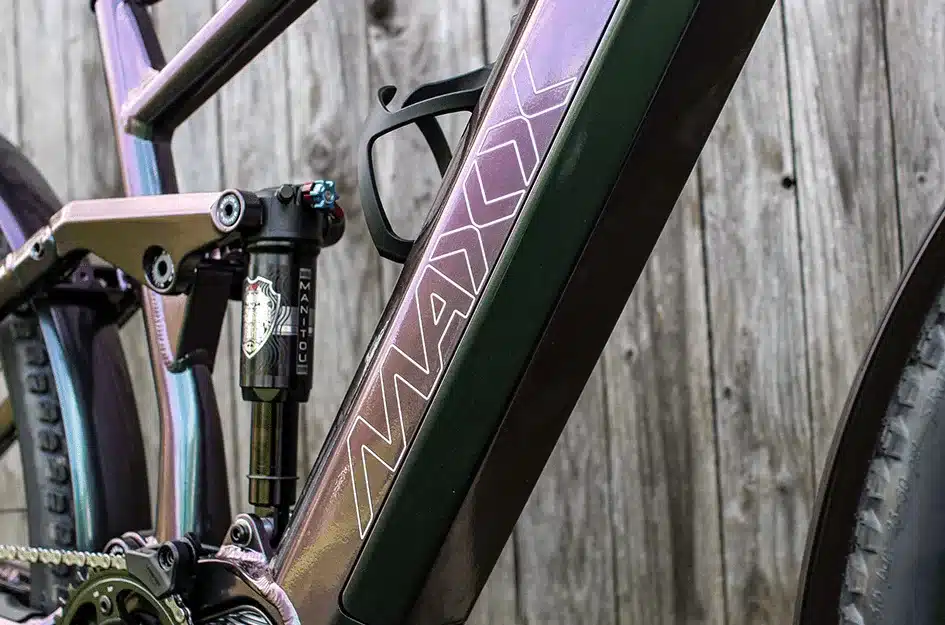 Nahaufnahme des Rahmens eines MAXX Tourmaxx ELS Tour E-Bikes, Fokus auf den Dämpfer und das Markenlogo.