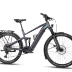 Seitenansicht eines violett-grün schimmernden MAXX Tourmaxx ELS Tour E-Bikes mit vollgefedertem Rahmen, Gepäckträger, Schutzblechen und breiten Reifen.
