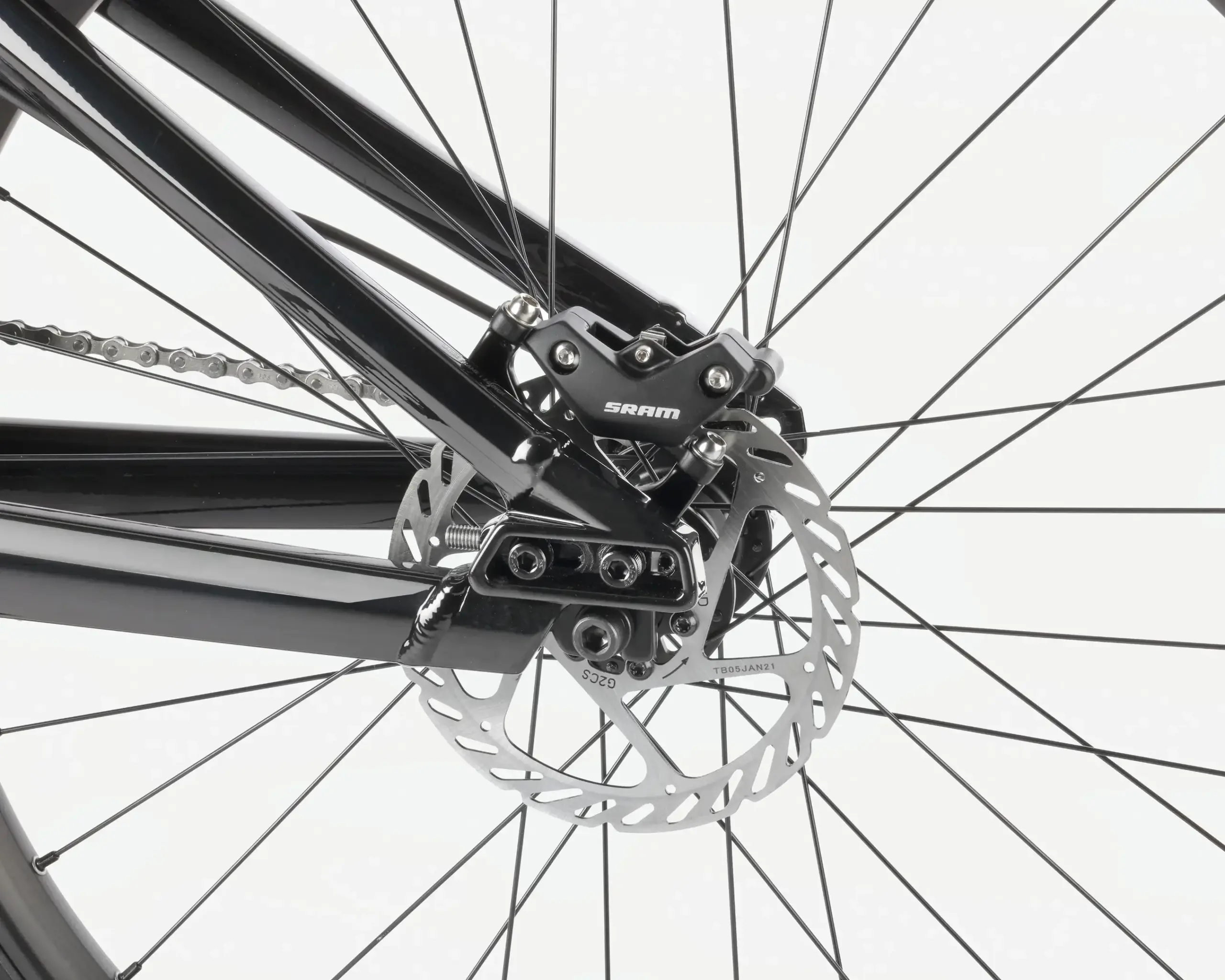 Nahaufnahme der Fahrradbremse am Hinterrad, mit Kette und Speichen sichtbar