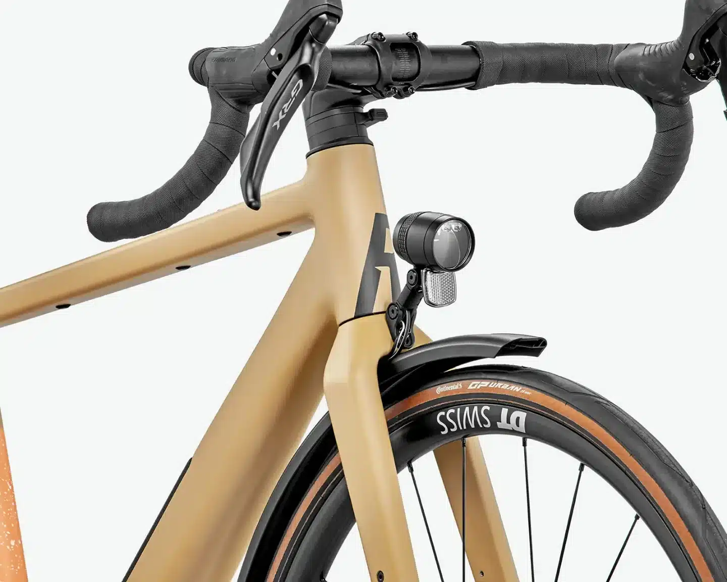 Nahaufnahme des vorderen Teils eines sandfarbenen ROSE Backroad AL EQ Gravelbikes, mit Fokus auf den Rennlenker, die integrierte Lichtanlage und das DT Swiss Laufrad.