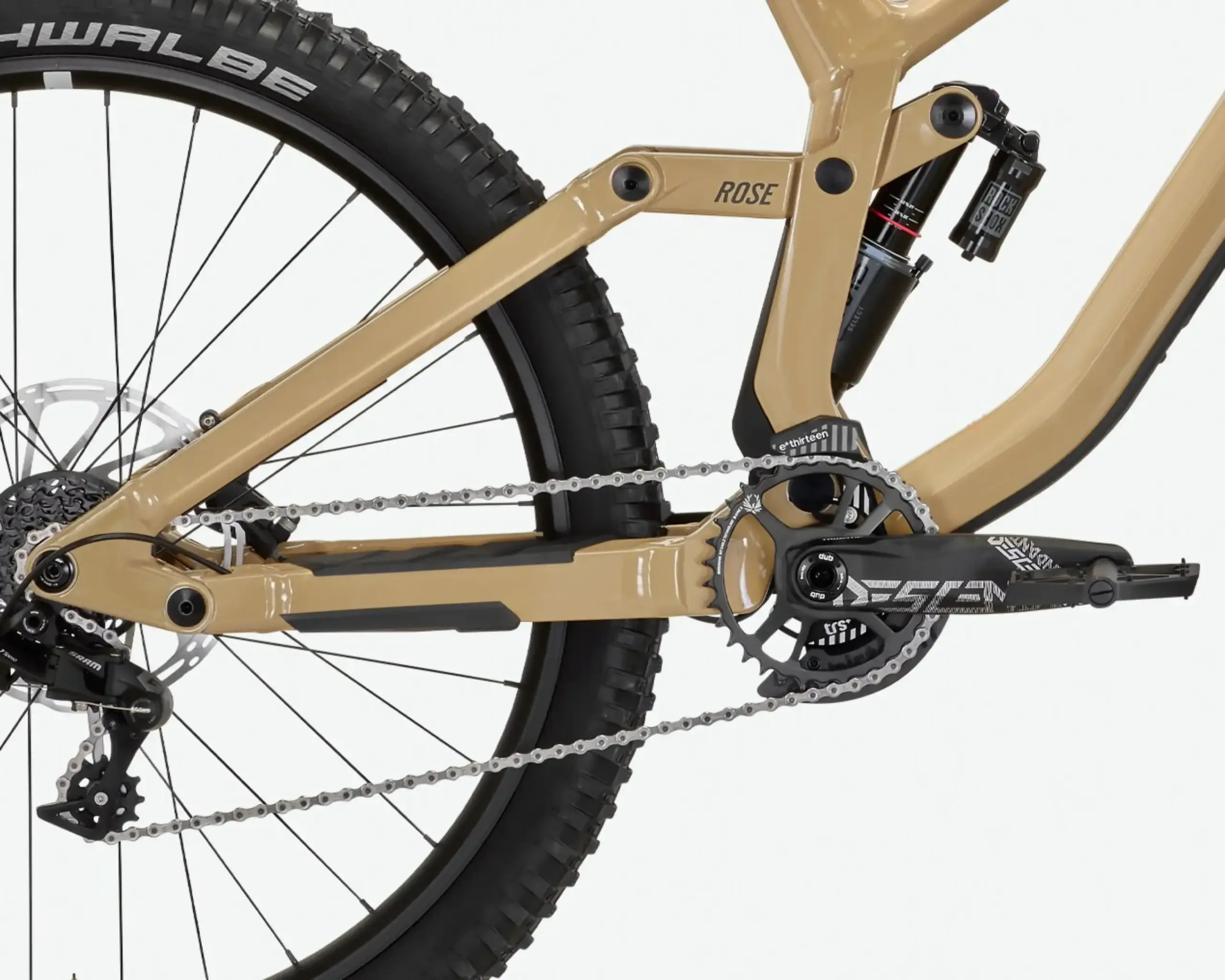 Detailaufnahme des goldfarbenen Rahmens eines Rose Scrub SC Mountainbikes, fokus auf die Hinterradaufhängung mit RockShox-Dämpfer und den SRAM-Antriebsstrang mit Kettenblatt und Kette.