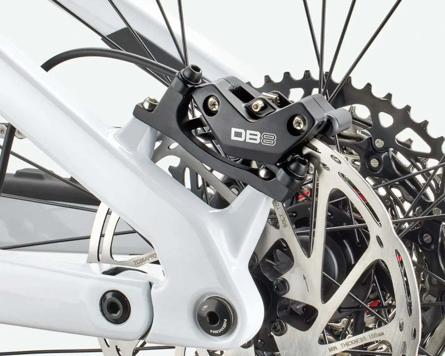 Nahaufnahme der Hinterradbremse und des Ritzelpakets eines weißen E-Mountainbikes mit der Aufschrift DB8 auf dem Bremssattel.