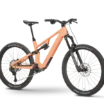 Rose File Plus XT E-MTB in der Farbe Koralle, von der Seite fotografiert mit einem schwarzen Hintergrund.