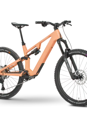Rose File Plus XT E-MTB in der Farbe Koralle, von der Seite fotografiert mit einem schwarzen Hintergrund.