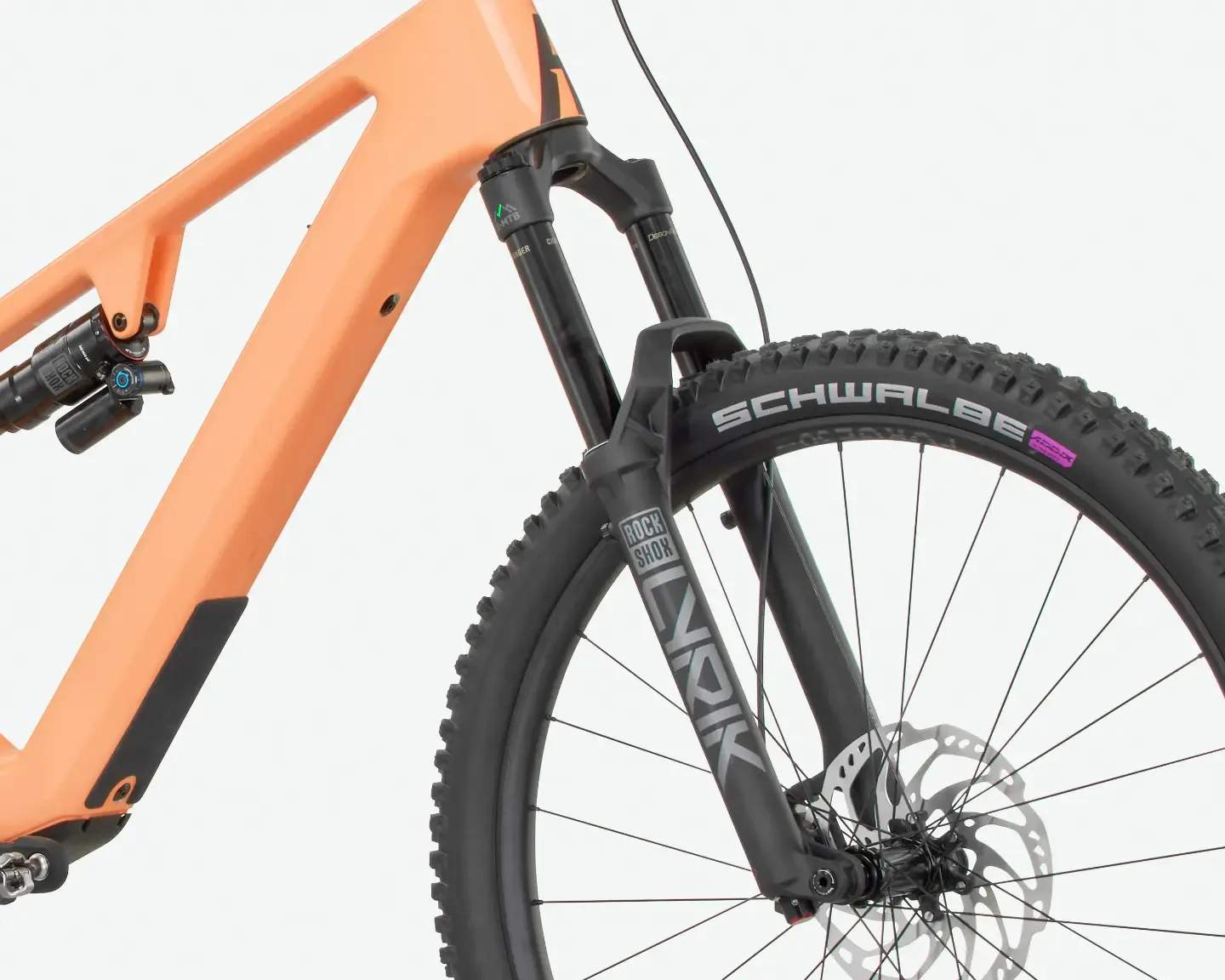 Detailaufnahme des orangefarbenen Rahmens eines Rose File Plus XT E-Mountainbikes, mit Fokus auf die RockShox Lyrik Federgabel, den Dämpfer am Hinterbau und den Schwalbe Tacky Chan Reifen.