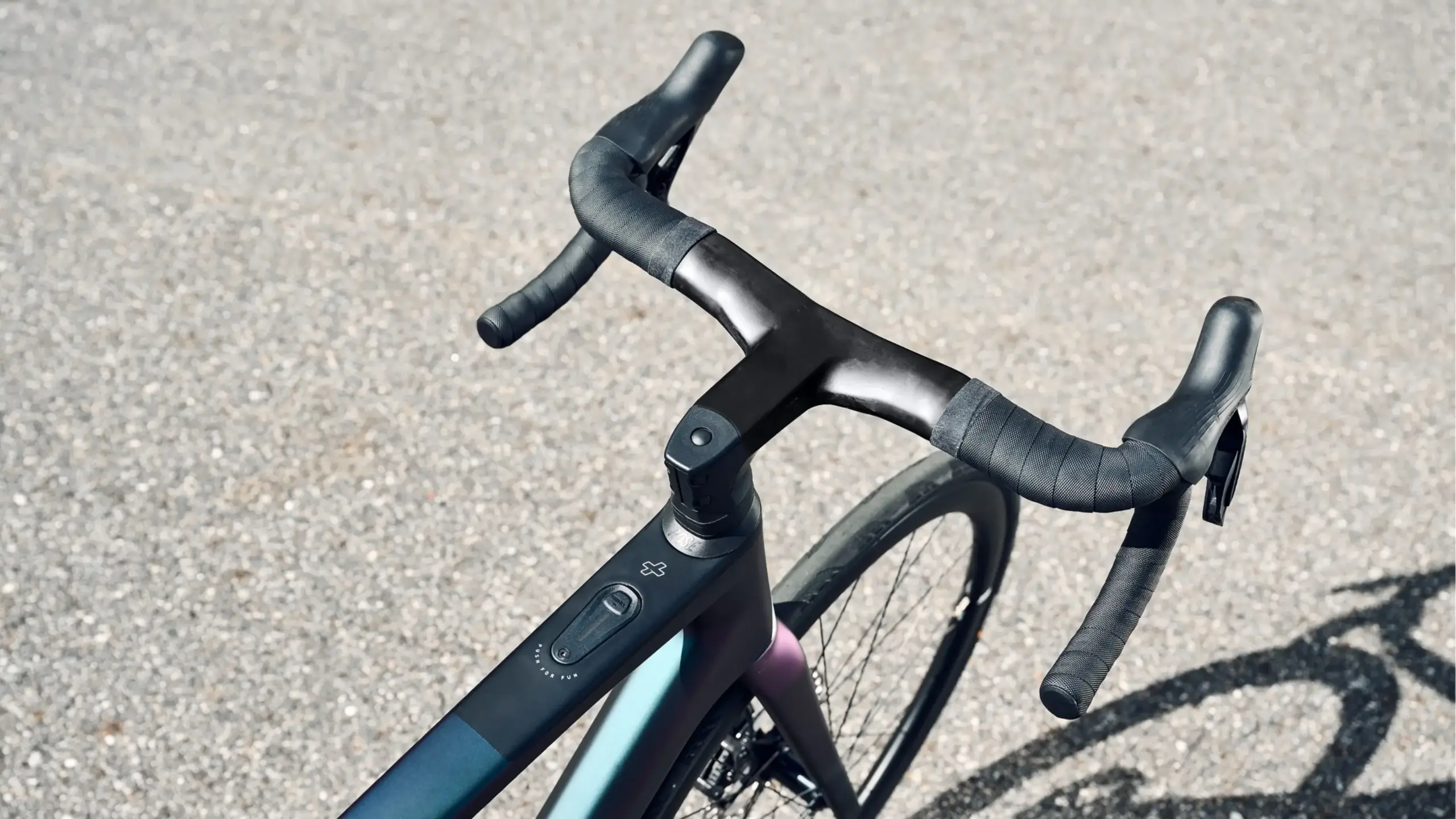 Detailansicht des Lenkers und Oberrohrs eines sportlichen E-Rennrads mit integrierten Bedienelementen.