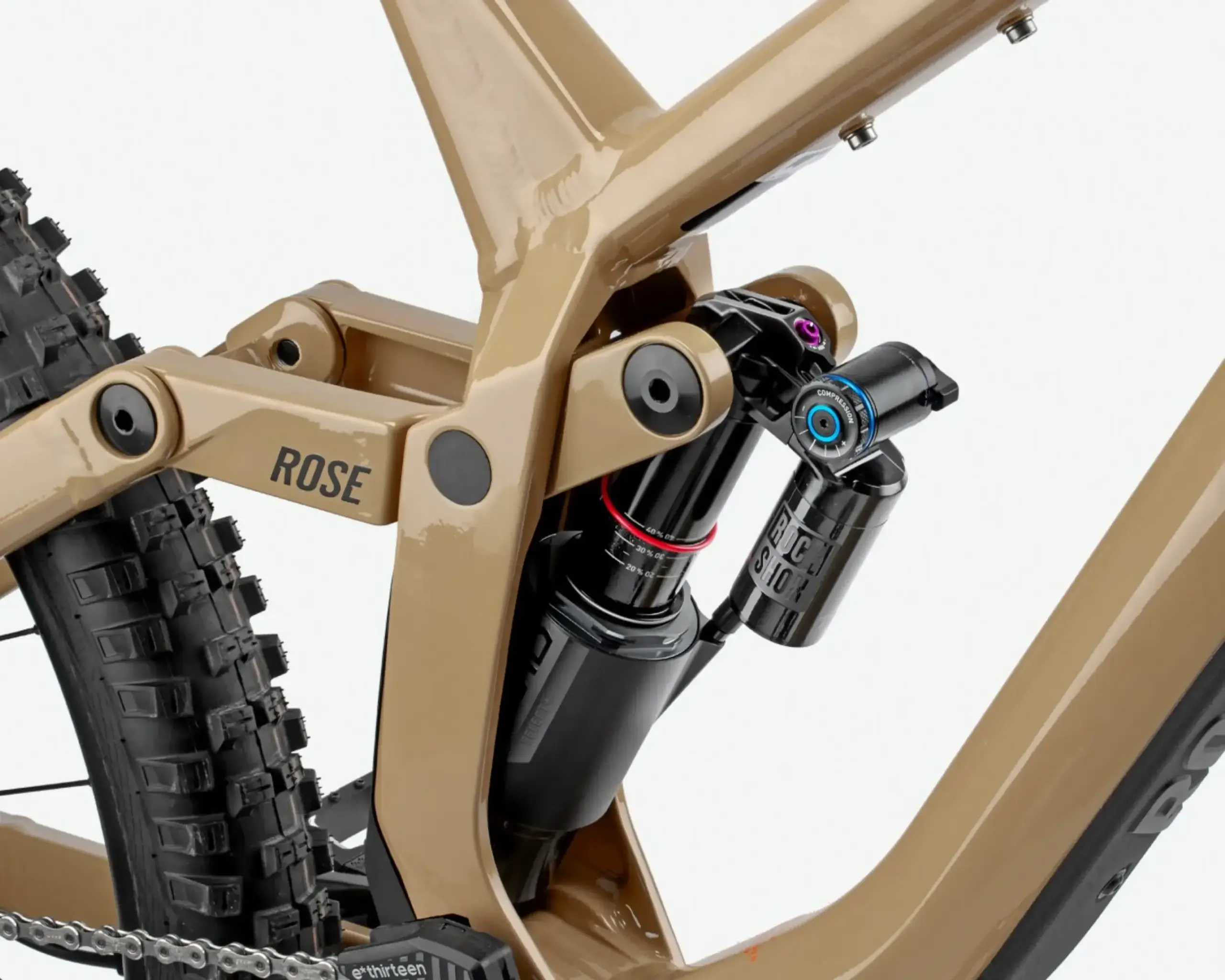 Nahaufnahme des goldbraunen Rahmens eines ROSE Scrub DC 2 Mountainbikes, Fokus auf den RockShox Federungsdämpfer und die Hinterradaufhängung, inklusive