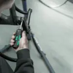 Nahaufnahme eines Mannes, der mit einem grünen und schwarzen Drehmomentschraubendreher eine Schraube am Lenker eines Fahrrads festzieht.