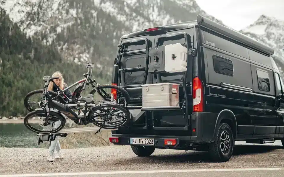 Fahrradträger Bike Carrier Swing am schwarzen Campervan mit montierten Fahrrädern vor Bergkulisse