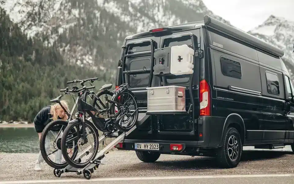 Fahrradträger Bike Carrier Swing am Heck eines Hymer-Campervans mit montierten Fahrrädern in alpiner Umgebung.