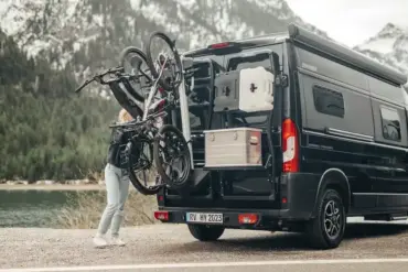 Bike Carrier Swing Fahrradträger am Fahrzeugheck mit aufgeladenen Fahrrädern bei geöffneter Schwenkfunktion vor Bergkulisse