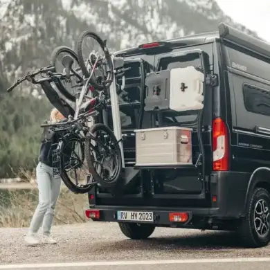 Bike Carrier Swing Fahrradträger am Fahrzeugheck mit aufgeladenen Fahrrädern bei geöffneter Schwenkfunktion vor Bergkulisse