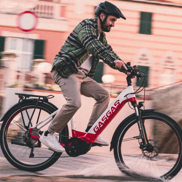 Mann mit Helm fährt ein rotes und weißes GASGAS E-Bike auf einer nassen Straße.