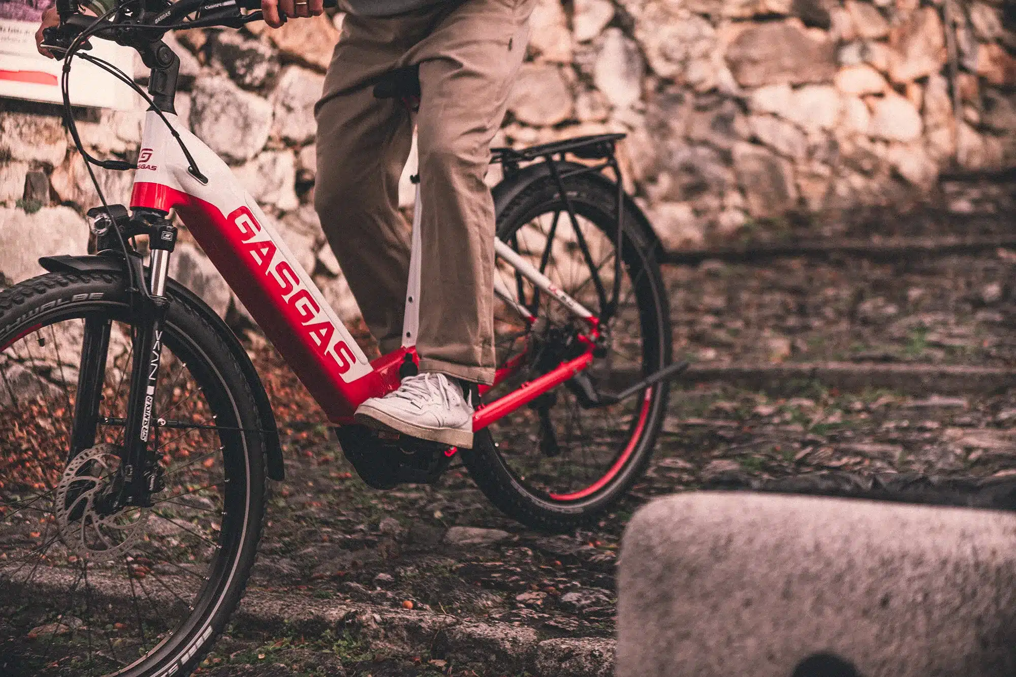 Detailansicht eines GASGAS G Trekking E-Bikes, das von einer Person auf einem unebenen Weg gefahren wird.