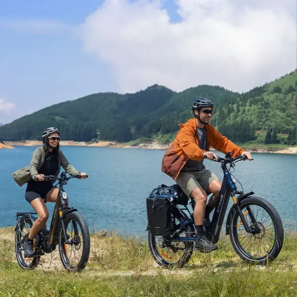 Ein Mann und eine Frau fahren nebeneinander auf ENGWE E26 3.0 Pro E-Bikes auf einem Feldweg neben einem See.