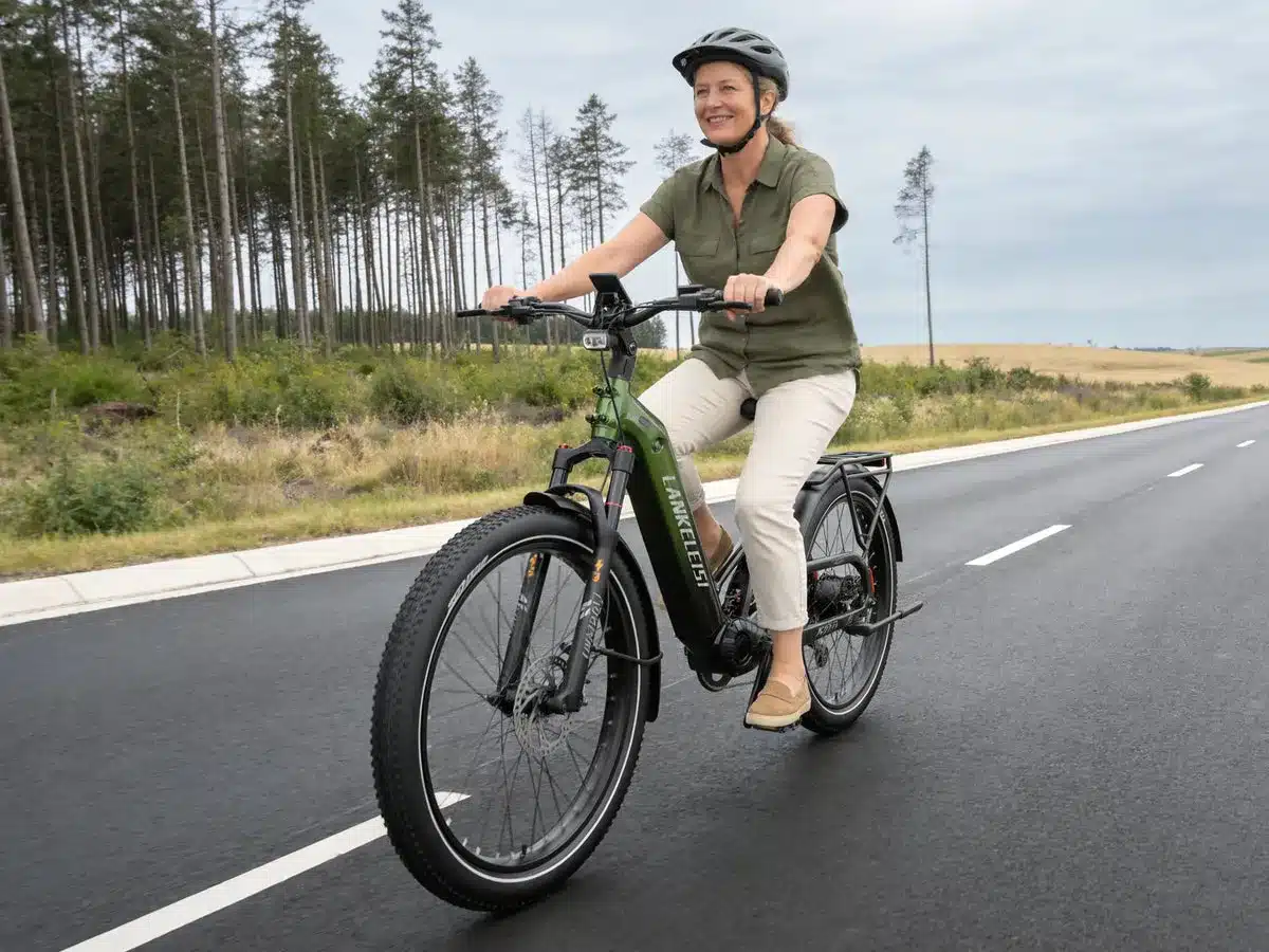 Frau fährt grünes Lankeleisi KETT-8 E-Bike mit Fat Tires und Vollfederung auf einer asphaltierten Straße.