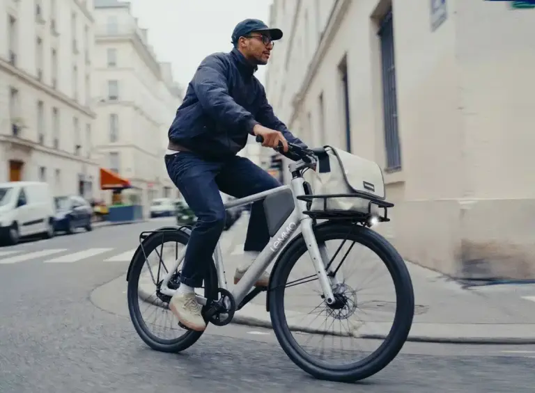 Ein Mann fährt ein Lemmo One Collab. Ride Fahrrad mit Gepäckträger und Tasche auf einer Straße.