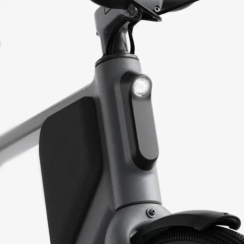 Detaillierte Ansicht des grauen Fahrradrahmens des Lemmo One Collab. Ride E+Bikes mit Fokus auf das integrierte Frontlicht und schwarze Seitenverkleidung.