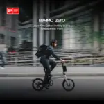 Mann mit Helm fährt ein Lemmo Zero faltbares E-Bike mit Rucksack auf dem Rücken auf einer Straße, im Hintergrund unscharfe Gebäude und eine Brücke.