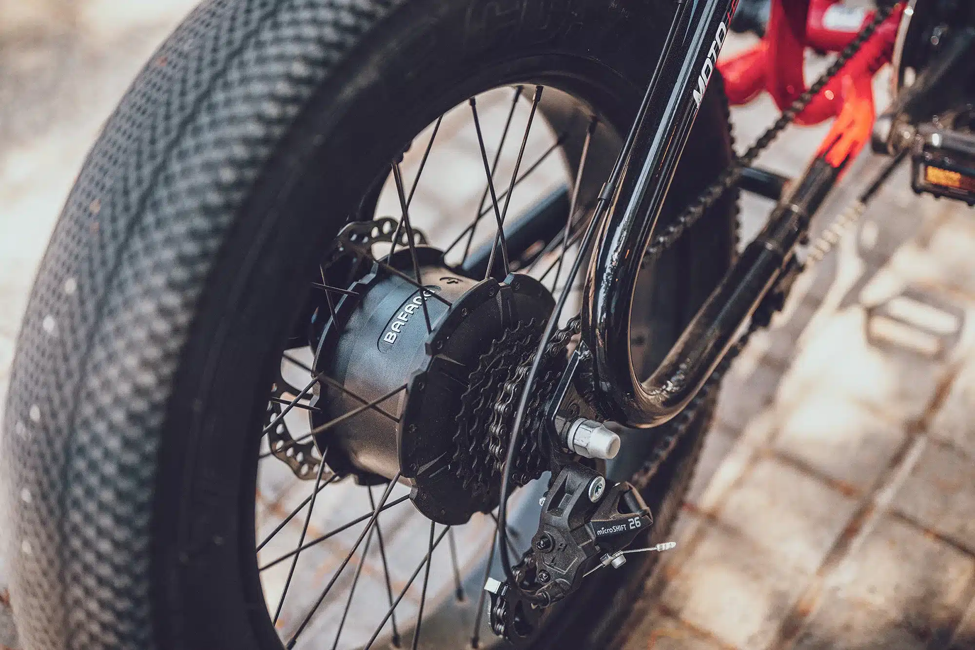 Nahaufnahme des Hinterrads eines MOTO E-Bikes, das den Nabenmotor und die Kettenschaltung zeigt.