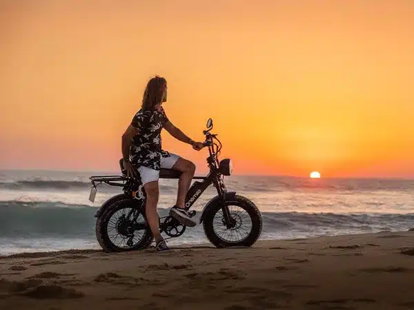 Mann auf Onemile Scrambler S Pro Fatbike am Strand.