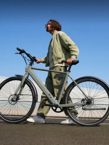 Ein Mann in legerer Kleidung schiebt ein graues TENWAYS CGO600 Pro E-Bike im Freien.