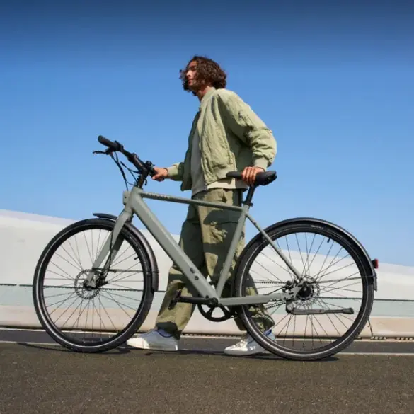 Ein Mann in legerer Kleidung schiebt ein graues TENWAYS CGO600 Pro E-Bike im Freien.