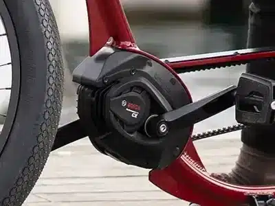 Detailaufnahme des Bosch Performance Line CX Motors mit Kurbel, Riemen und Reifen eines roten E-Bikes