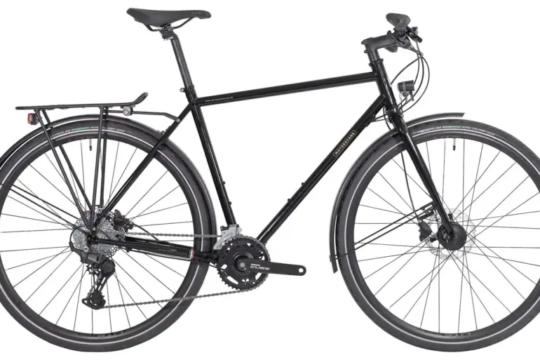 Schwarz lackiertes Motobécane Randonneur Fahrrad mit Gepäckträgern, Schutzblechen und breiten Reifen.