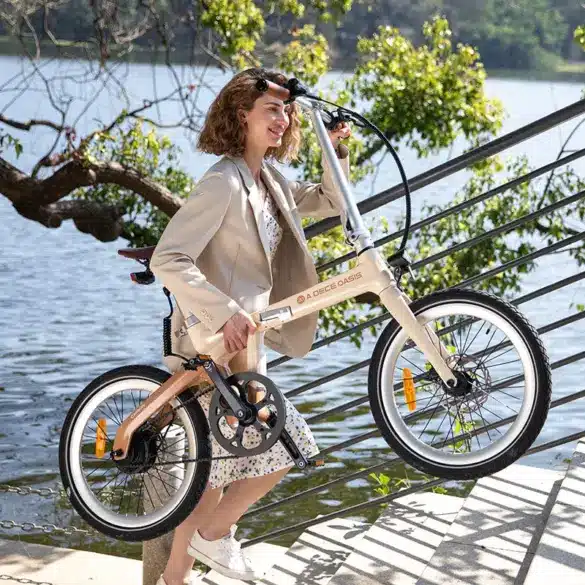 Frau mit beigem Blazer und Kleid trägt ein ADO Air Carbon Faltrad im Freien neben einer Treppe und einem Fluss.