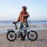 Frau mit ADO Air Carbon Pro Faltrad am Strand mit Meer im Hintergrund