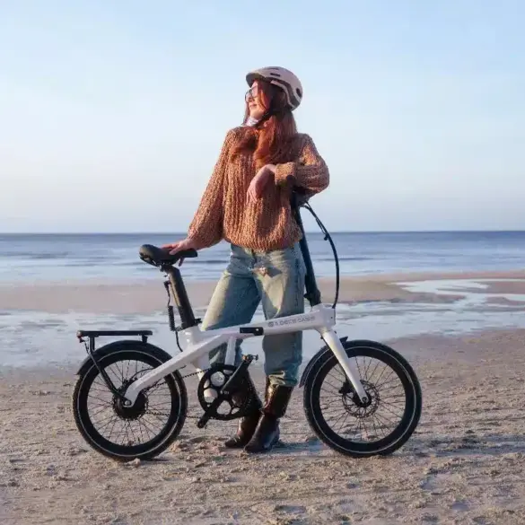 Frau mit ADO Air Carbon Pro Faltrad am Strand mit Meer im Hintergrund