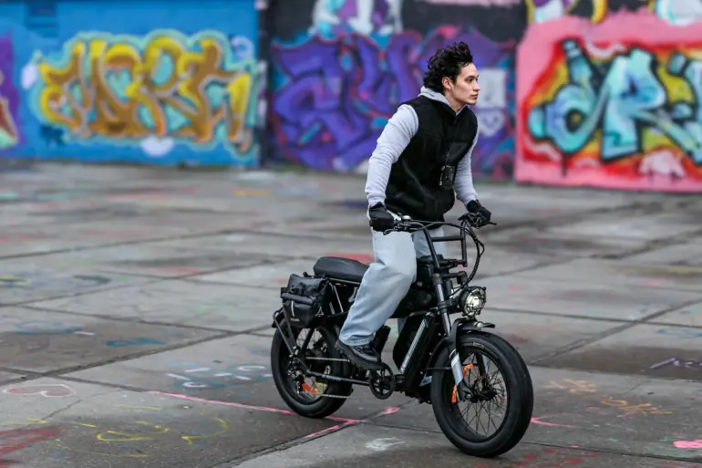 Mann fährt ein CAVET Air E-Bike mit breiten Reifen und auffälliger Optik auf einem von Graffiti-Tags bedeckten Untergrund
